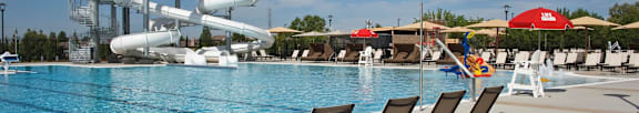 A pool with a water slide and lounge chairs.