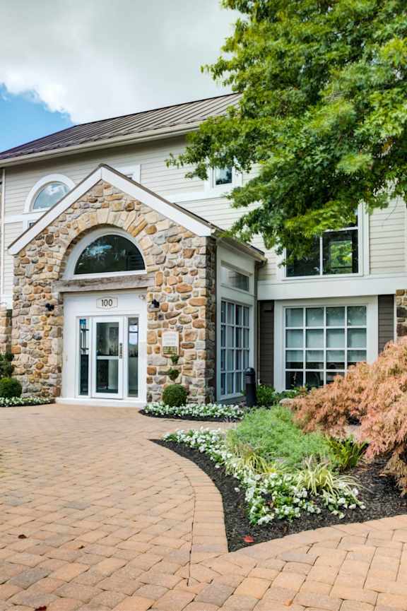 A house with a stone arched doorway and a brick pathway leading to it.