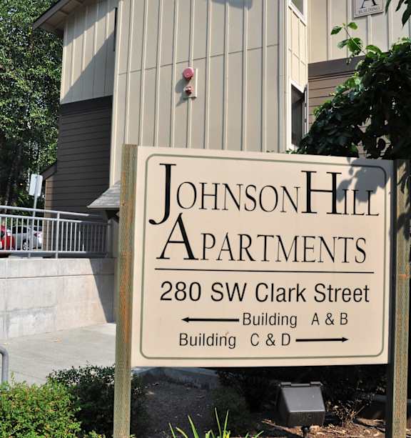 A sign for Johnson Hill Apartments is in front of a building.