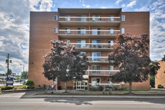 a brick apartment building on a street corner with trees