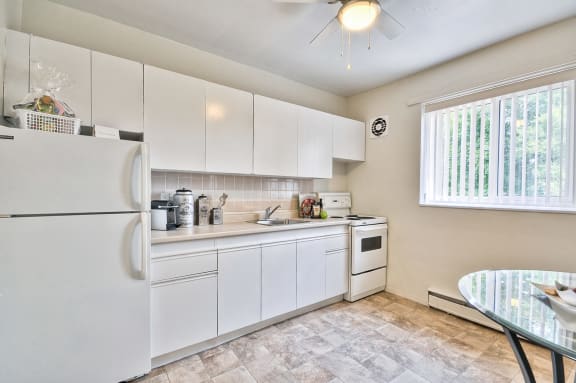 a kitchen with white cabinets and appliances and a table