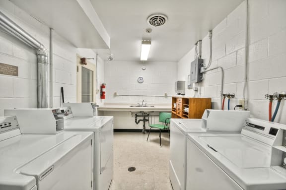 a laundry room with three washing machines and a sink