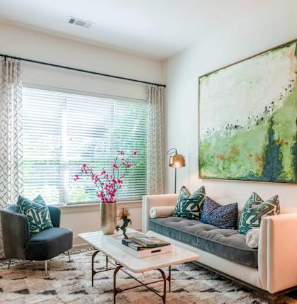 A living room with a couch, chair, and a painting on the wall.