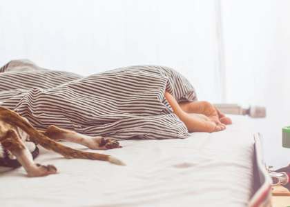 a woman sleeping on a bed under a blanket