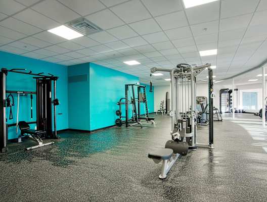 a gym with weights and cardio equipment and a blue wall at Presidio Palms Apartments, Tucson