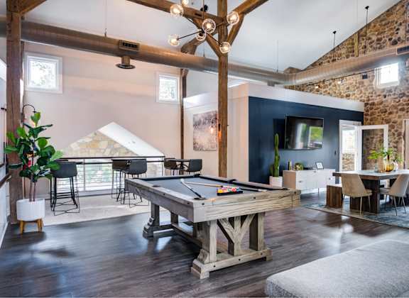 A pool table is in the middle of a room with a blue wall and a TV.