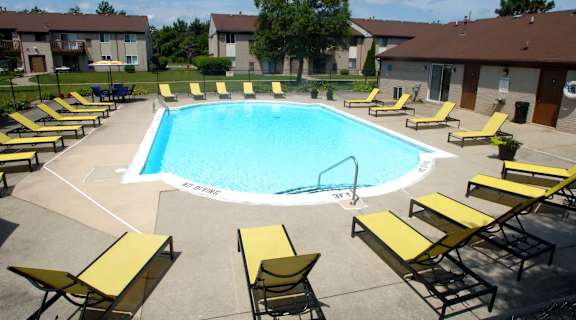 a swimming pool with yellow lounge chairs around it