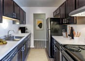 Thumbnail 1 of 4 - A kitchen with black cabinets and a stainless steel refrigerator.