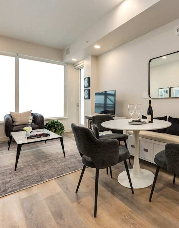 A modern home office with a desk, chairs, and a large window.