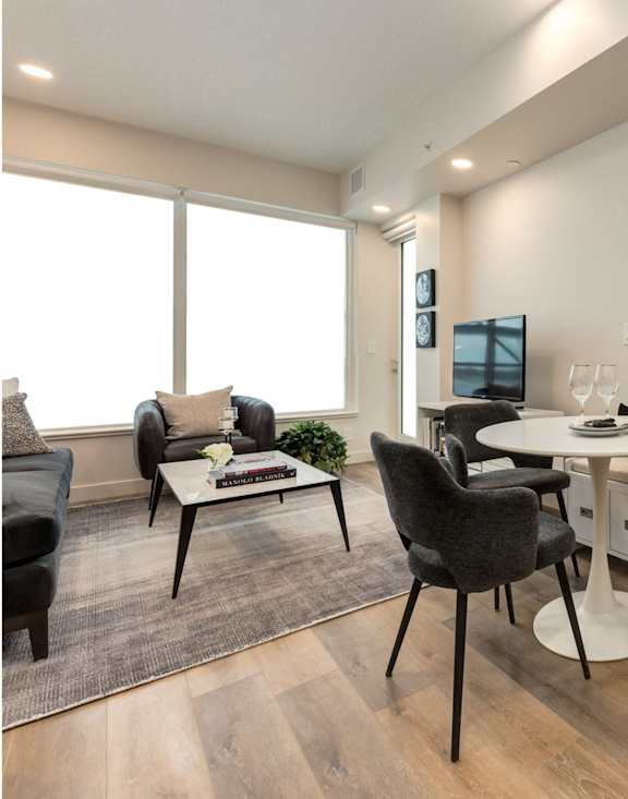 A modern home office with a desk, chairs, and a large window.