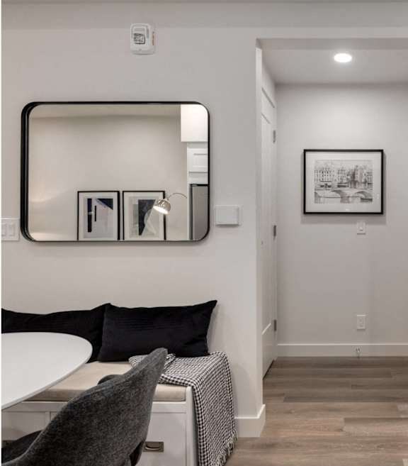 A hallway with a mirror, a bench, and a picture on the wall.