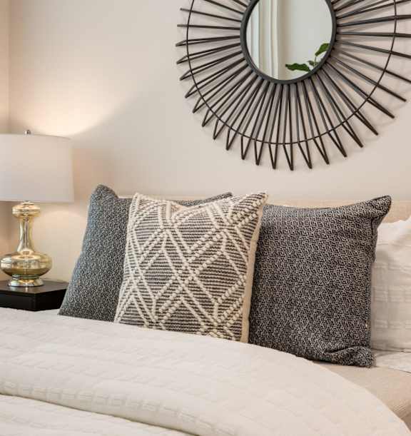 A bed with a white comforter and four pillows with different patterns.