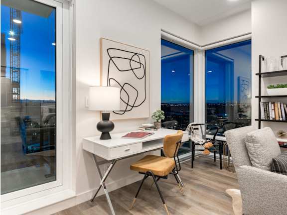 A modern room with a desk, chair, and a large window overlooking the city.