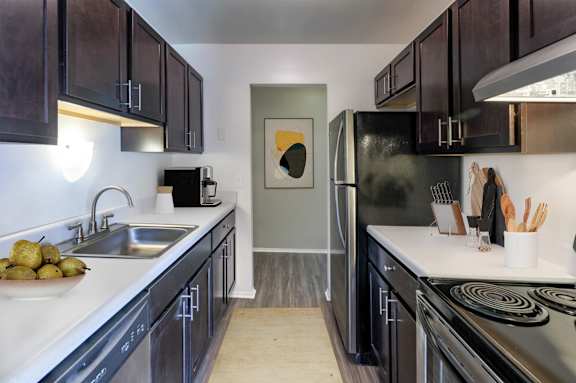 A kitchen with black cabinets and a stainless steel refrigerator.