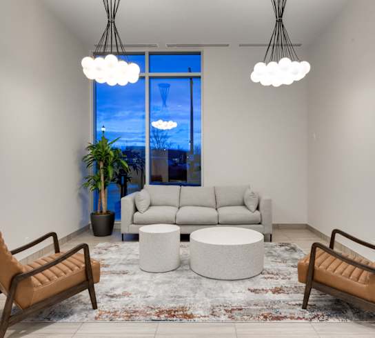 A living room with a large window, a sofa, a chair, a table, and a rug.