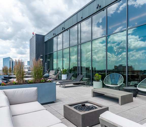 A modern outdoor seating area with white furniture and a fire pit.