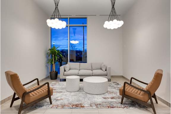 A living room with a large window, a sofa, a chair, a table, and a rug.
