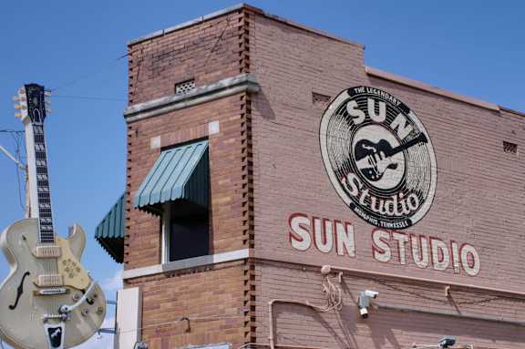 A guitar is leaning against a brick building with a sign that says Sun Studio.