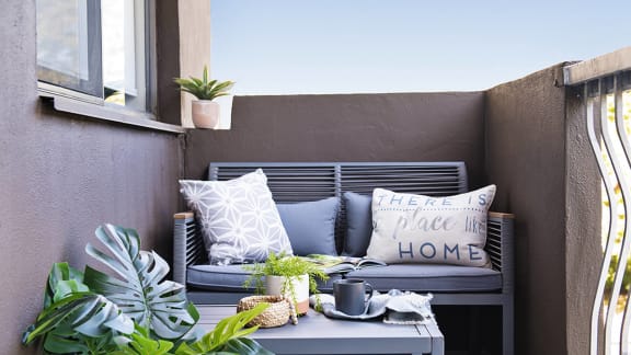 a seating area with a couch and pillows on a balcony