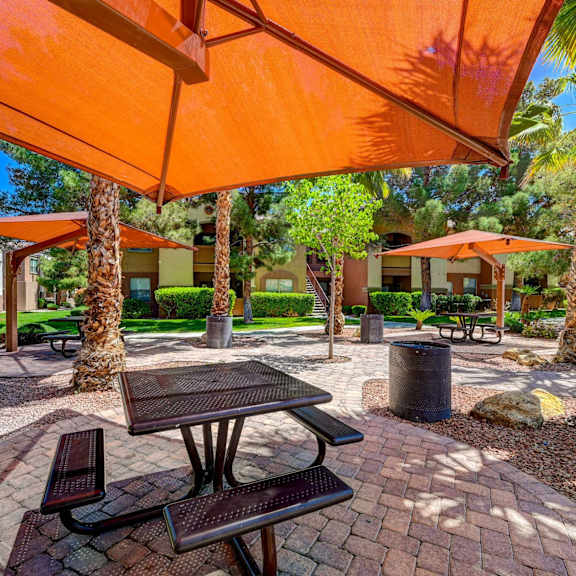 A patio with a table and chairs under an orange umbrella.