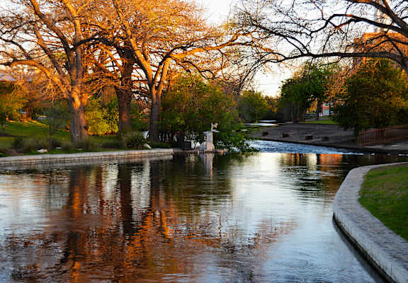 A tree-lined canal with a boat tied to a dock.