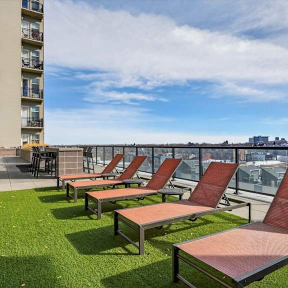 A row of red lounge chairs are on a grassy patio.