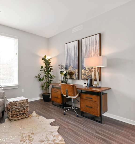 A room with a grey couch, a wooden desk, and a white wall.