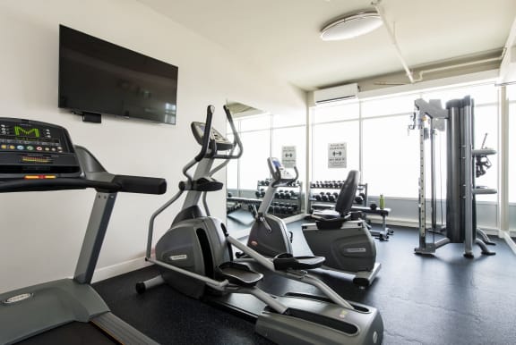 a gym with cardio equipment and a tv on the wall