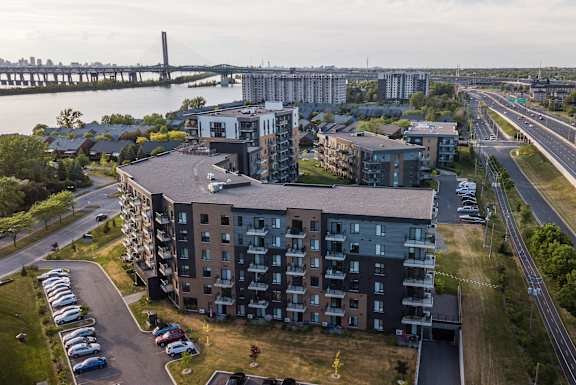 an aerial view of an apartment complex with a river and a bridge in the background