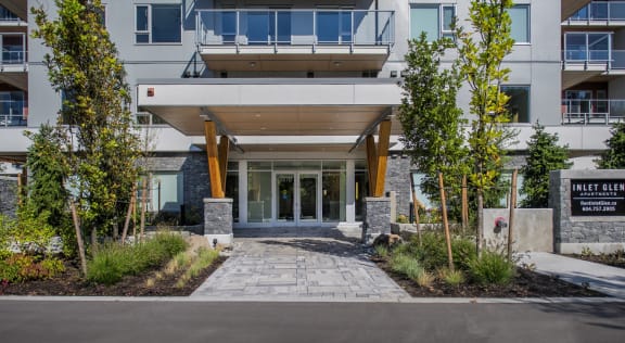 the entrance to an apartment building with a stone walkway and trees