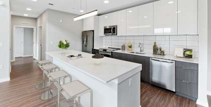 A modern kitchen with a long white island and stainless steel appliances.