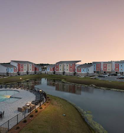 a building with a pool and a lake at dusk