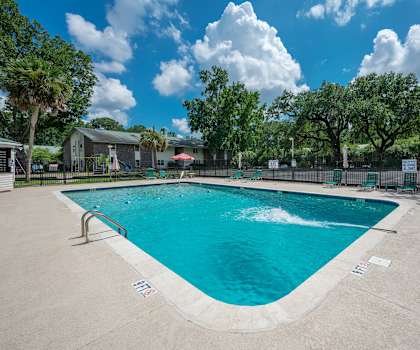 A large outdoor swimming pool surrounded by a fence and trees. at Brackenbrook Apartments, North Charleston 29418