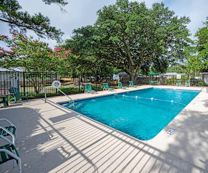 A pool surrounded by trees and a fence with a no swimming sign. at Woodlocke Apartments, South Carolina, 27461