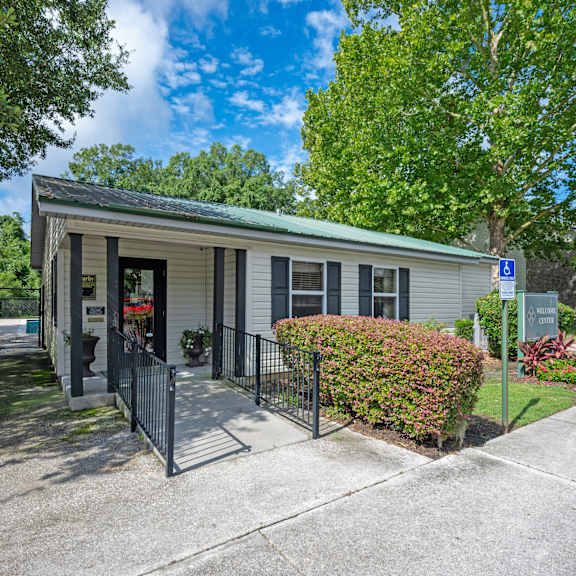 A white house with a green lawn and pink flowers in front. at Sawbranch Apartments, Summerville 29485
