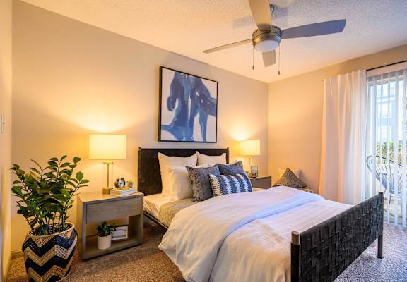 A bedroom with a large bed and a ceiling fan.