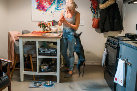 a woman standing in a kitchen with her dog