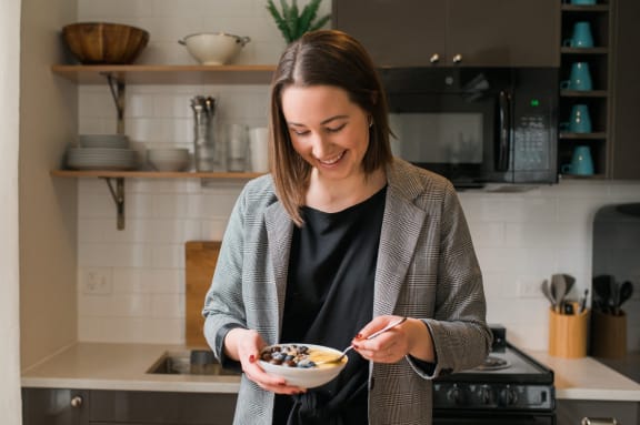 a woman eating cereal from a bowl in a kitchen