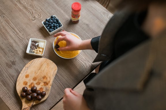 a person putting fruit into a bowl on a wooden table