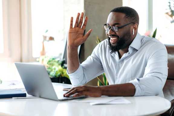 a man sitting at a laptop computer with his hand in the air