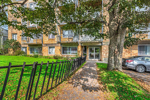 A large brick apartment building with a green lawn in front.
