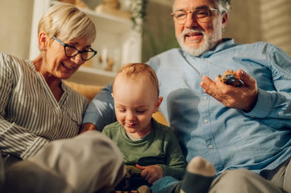 a family sitting on a couch with a baby playing with a toy