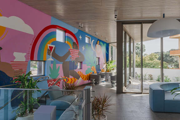 a large mural in a living room with blue furniture and a glass railing