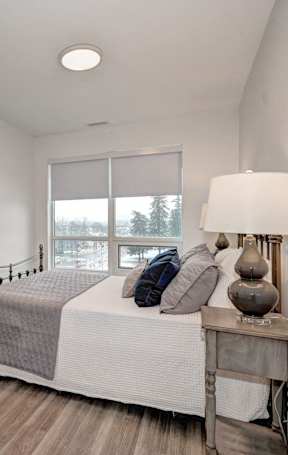 A bedroom with a bed, nightstand, and window.