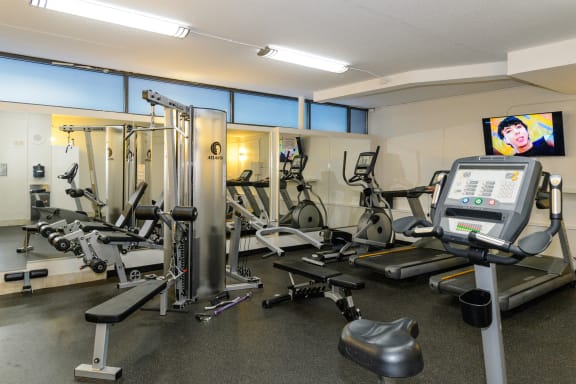 a gym with exercise equipment and a tv with a woman on it
