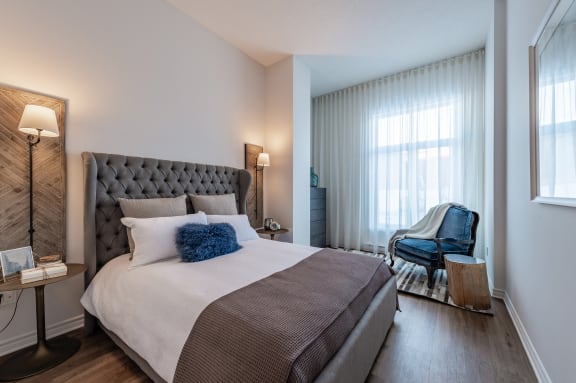 a bedroom with a bed and a chair and a window