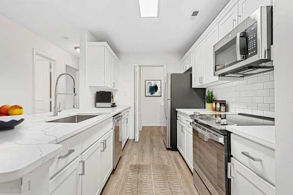 A modern kitchen with white cabinets and a black refrigerator.
