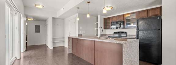 A kitchen with a black fridge and wooden cabinets. at Wilmington Flats Apartments, Salt Lake City, UT, 84106