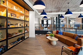A modern living room with a long wooden shelf on the left side and a brown sofa in the center.