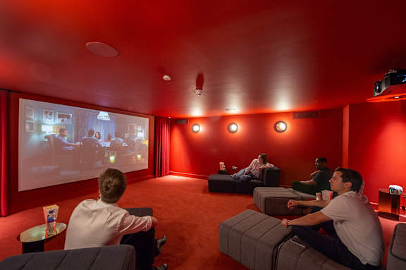 People are sitting in a room watching a movie on a large screen.